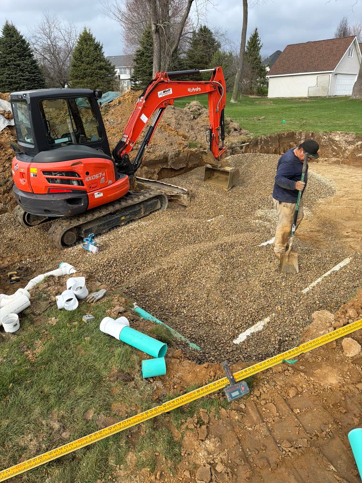 Worker grading gravel for a new drain field with a Kubota mini-excavator